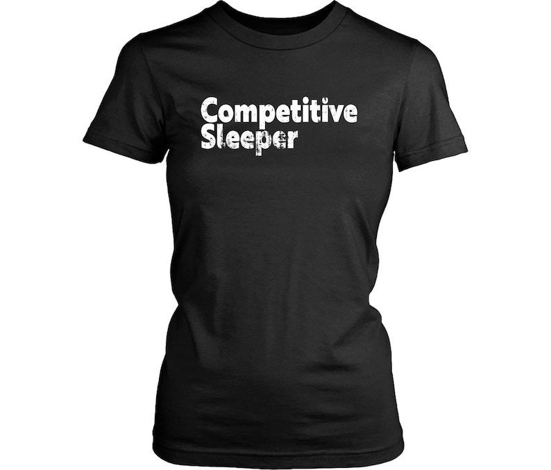 May include: Black t-shirt with the white text "Competitive Sleeper". The shirt has a crew neck and short sleeves. The text has a distressed, textured appearance.