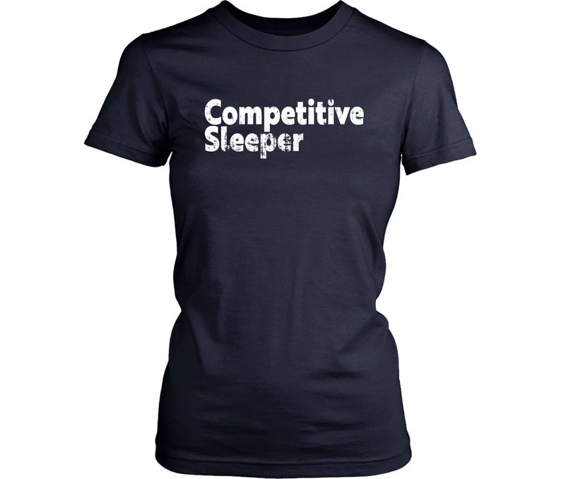 May include: Navy blue t-shirt with the white text "Competitive Sleeper". The shirt has short sleeves and a crew neck. The text has a distressed, slightly textured appearance.
