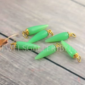Puede incluir: Seis colgantes de piedra preciosa verde con detalles dorados. Los colgantes tienen forma de lágrima con una punta puntiaguda.