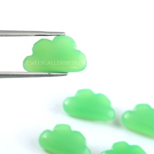 May include: Five green cloud-shaped cabochons, one held by tweezers. The cabochons are smooth and polished, with a light green colour.