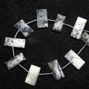 May include: A strand of white and black dendritic opal beads, strung on a silver wire. The beads are rectangular in shape and have a natural, organic look.