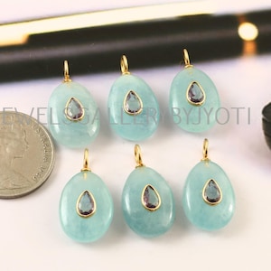 Può includere: Sei pendenti con pietre preziose acquamarina con anelli dorati. Ogni pendente ha una pietra di ametista a forma di goccia incastonata in una lunetta dorata. Le pietre di acquamarina sono di forma ovale e di colore azzurro.