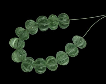 May include: A strand of light green glass beads with a faceted, ribbed texture. The beads are strung on a thin wire.