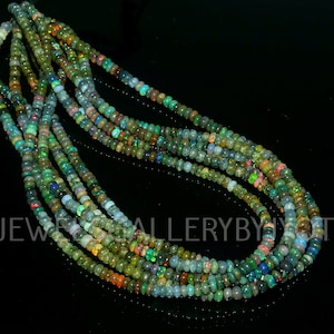May include: A strand of multi-colored opal beads. The beads are small and round, and they are strung on a clear thread. The beads are a mix of green, blue, and red.