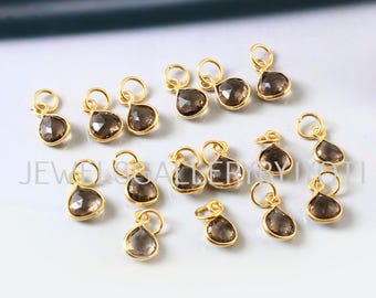 May include: A collection of 16 gold-plated teardrop-shaped charms with smoky quartz gemstones. The charms are perfect for jewelry making and crafting.