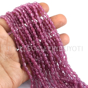 Könnte beinhalten: Eine Strähne rosafarbener, ovaler Edelsteinperlen. Die Perlen sind auf einem durchsichtigen Faden aufgefädelt und haben einen Durchmesser von etwa 6 mm.