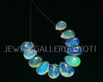 May include: A strand of iridescent opal gemstone beads, each bead is a teardrop shape with a light blue and white color.