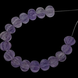 May include: A strand of light purple amethyst beads, each bead is faceted and has a rounded shape. The beads are strung on a thin wire.