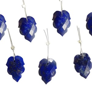 May include: Six blue lapis lazuli gemstone pendants with silver bail. Each pendant is shaped like a leaf with a faceted design.