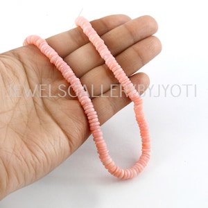 May include: A strand of pink coral beads, approximately 18 inches long, with a smooth, polished finish. The beads are round and have a slightly irregular shape. The coral is a pale pink color and has a natural, organic look.