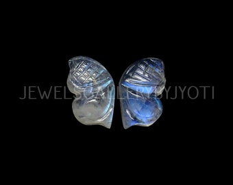 May include: Two carved butterfly wings made of iridescent blue labradorite gemstone. The wings are carved with intricate details and have a shimmering, opalescent quality.