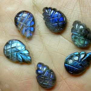 May include: Six carved labradorite gemstones in the shape of pineapples. The gemstones are a deep blue with iridescent flashes of green and gold.
