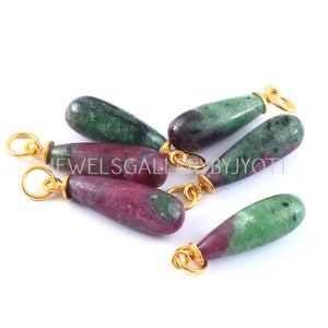 May include: Six green and pink gemstone pendants with gold jump rings. The gemstones are teardrop shaped and have a mottled appearance.