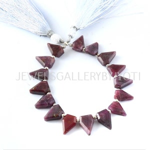 May include: A strand of 15 faceted, triangular, ruby red gemstone beads with silver spacers. The beads are strung on a silver chain and are approximately 1 inch in length.