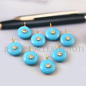 May include: Eight turquoise-colored, round pendants with gold-colored bails. Each pendant features a central, clear, round gemstone. The text "JEWELS GALLERY JYOTI" is visible in the image.