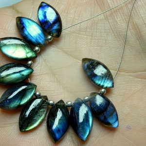 May include: A strand of iridescent blue and green labradorite gemstone beads in a marquise shape. The beads are strung on a silver wire.