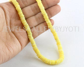 May include: A strand of pale yellow shell beads, strung together to form a necklace. The beads are small and round, with a slightly irregular shape.
