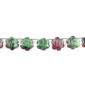 May include: A strand of green and red gemstone beads in a flower shape.