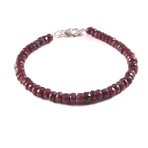 May include: A red gemstone bracelet with a silver clasp. The bracelet is made of small, faceted beads.