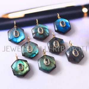 May include: A collection of hexagonal labradorite pendants with gold-colored bails. Each pendant features a central oval-shaped stone. The labradorite stones display a range of blue and green hues.