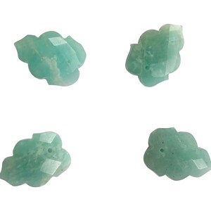 May include: Four green, carved, gemstone beads with a hole in the center. The beads are shaped like a cloud or a flower.