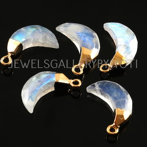 May include: Five crescent moon shaped rainbow moonstone pendants with gold-toned metal bail loops.