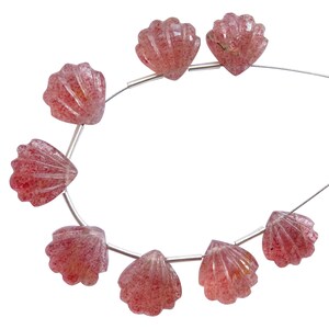 May include: A strand of pink and red gemstone beads shaped like seashells. The beads are strung on a silver wire.