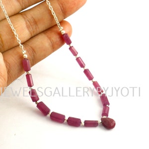 Może przedstawiać: Srebrny naszyjnik z łańcuszkiem, z wisiorem w kształcie łzy z rubinu i prostokątnymi koralikami z rubinu.