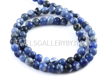 May include: A strand of blue and white gemstone beads. The beads are round and have a smooth, polished finish. The beads are strung on a clear thread.