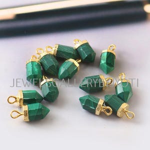 May include: A group of ten green malachite gemstone pendants with gold-plated caps and jump rings. The pendants are in the shape of a pointed teardrop.