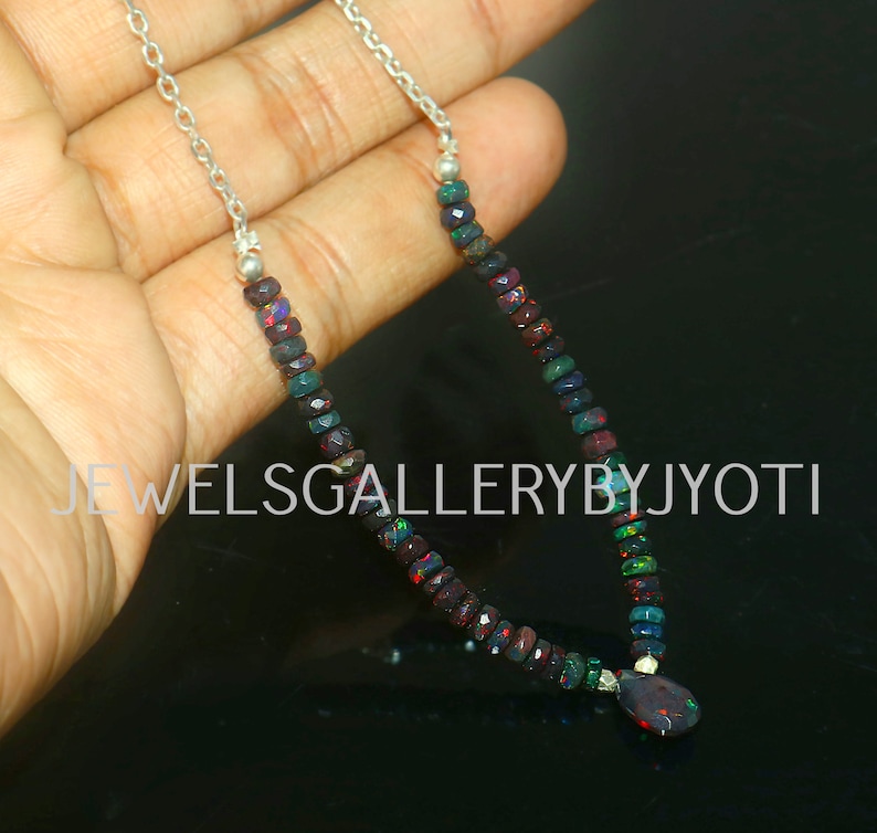 Pode incluir: Um colar de corrente de prata com um pingente feito de opala escura e iridescente. O colar &eacute; feito de pequenas contas de opala facetadas em tons de preto, verde e vermelho.