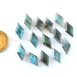 May include: A collection of 15 faceted labradorite gemstone cabochons in a kite shape. The stones are a mix of blue, green, and gray with iridescent flashes.