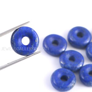 Könnte beinhalten: Ein Satz von sieben donutförmigen Lapislazuli-Perlen. Die Perlen sind tiefblau mit goldenen Flecken. Die Perlen sind alle ungefähr gleich groß und haben ein Loch in der Mitte zum Aufziehen.