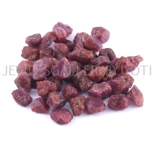 Puede incluir: Un montón de piedras preciosas de rubí rojo en bruto. Los rubíes son de varios tamaños y formas, con un color rojo intenso.