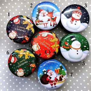 Könnte beinhalten: Sieben runde Weihnachts-Dosen mit verschiedenen Designs. Die Dosen zeigen den Weihnachtsmann, einen Schneemann, ein Rentier und den Text "A Merry Christmas".