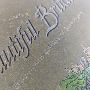 May include: A vintage book cover with the title "Beautiful Britain" and the subtitle "The Scenery and the Splendours of the United Kingdom". The cover is a dark green color with gold lettering and a small illustration of a building and trees.