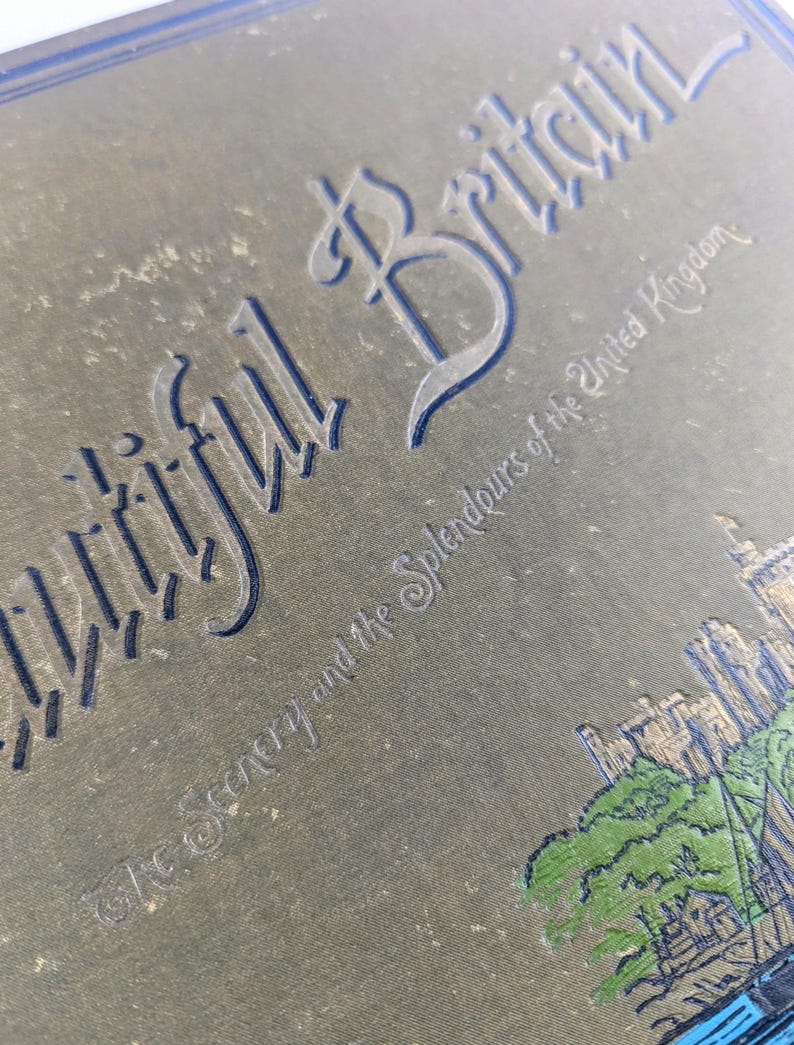 May include: A vintage book cover with the title "Beautiful Britain" and the subtitle "The Scenery and the Splendours of the United Kingdom". The cover is a dark green color with gold lettering and a small illustration of a building and trees.