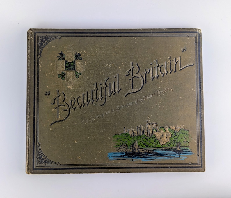 May include: A green and gold book cover with the title "Beautiful Britain" and a small illustration of a castle and a boat on the water.