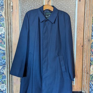 May include: A navy blue raincoat with a single button closure and two pockets. The label on the coat reads "Robert Hall".