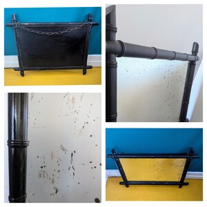 May include: A black bamboo framed mirror with a slightly distressed, aged look. The mirror is rectangular and has a simple design.