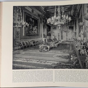 May include: A black and white photograph of a grand reception room in Windsor Castle. The room is decorated in the style of Louis XIV, with ornate chandeliers, a large fireplace, and a patterned carpet. The room is furnished with chairs, sofas, and tables.