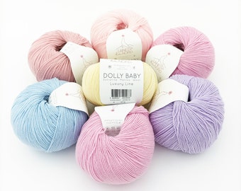 May include: Six balls of yarn in various pastel colors, including light pink, pale yellow, baby blue, lavender, and a deeper pink. The yarn is labeled "Dolly Baby" and "Luxury Line" with a barcode.
