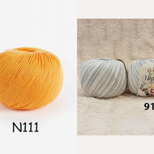 May include: Two balls of yarn, one orange and one blue and white striped. The orange ball is labelled N1111. The blue and white ball is labelled 912 and DMC Natura Just Cotton.