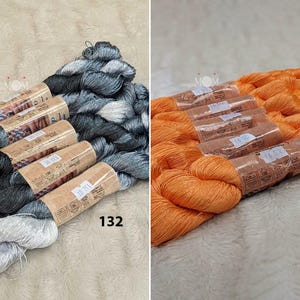 以下が含まれることがあります： 刺繍糸のセットが2つ、1つは銀と黒、もう1つはオレンジです。糸は、"132"と"220"と書かれた紙巻きボビンに巻かれています。
