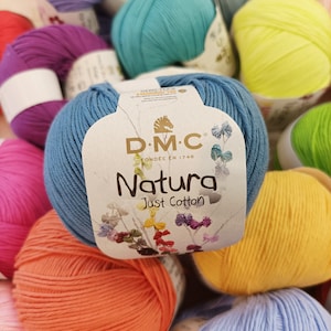 May include: A close-up of a variety of colourful yarn balls, including blue, green, yellow, orange, pink, and purple. The yarn is labelled "DMC Natura Just Cotton".