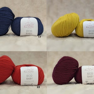 May include: Four skeins of yarn in different colors: navy blue, yellow, red, and burgundy. Each skein has a label that reads "Laines du Nord Eco Baby Luxury Line" with a corresponding color number.