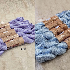 以下が含まれることがあります： ラベンダーとライトブルーの2つのメタリック刺繍糸の束。束には450と506の番号が付けられています。