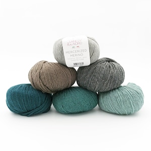 May include: Six balls of yarn in various shades of green, grey, and brown. The yarn is labelled "Mercerized Merino" and "Luxury Line" by "Laines du Nord".