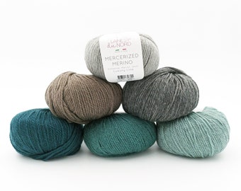 May include: Six balls of yarn in various shades of green, gray, and brown. The yarn is labeled "Mercerized Merino" and "Luxury Line" by "Laines du Nord".