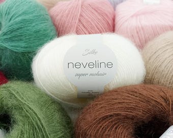 May include: A close-up of a variety of soft, fuzzy yarn skeins in different colors, including green, pink, white, brown, and beige. The yarn is labeled "Silke neveline super mohair".